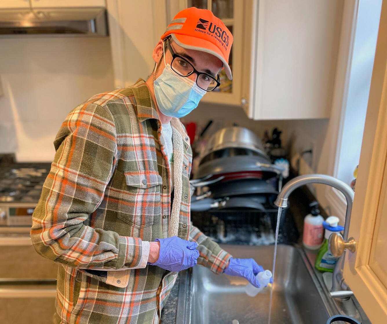 Person collecting water sample from kitchen sink