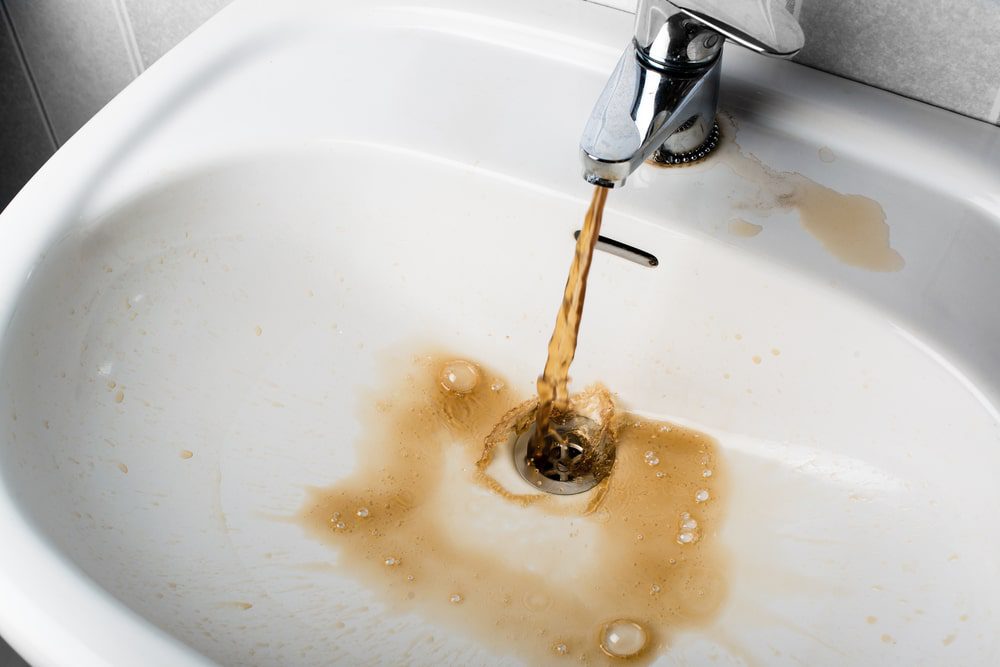Bathroom sink with brown water and stains